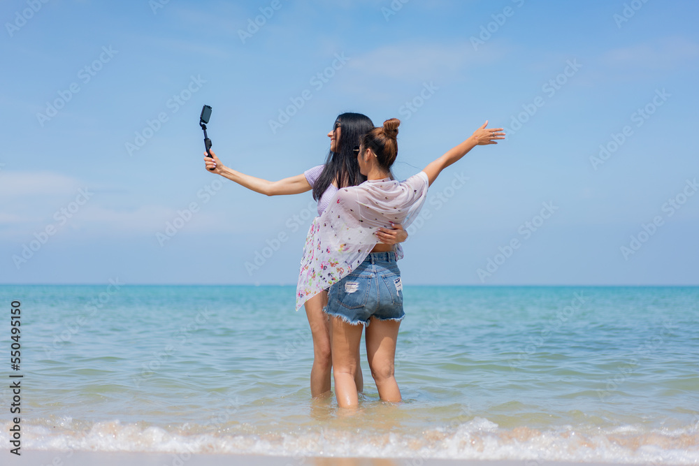 Two girlfriends hugging up and enjoying on the sea beach. A pair of girls in love cuddling on a tropical beach. romantic young lesbian couples in love and walking together on the beach.Concept of LGBT Two girlfriends hugging up and enjoying on the sea beach. A pair of girls in love cuddling on a tropical beach. romantic young lesbian couples in love and walking together on the beach.Concept of LGBT