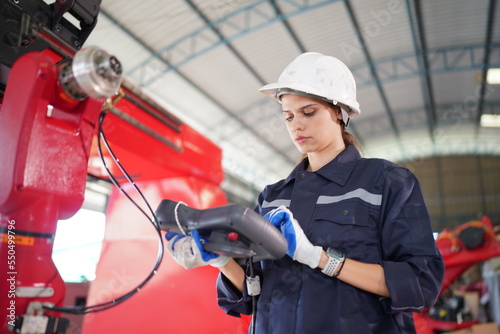 Robotics engineer working on maintenance of modern robotic arm in factory warehouse