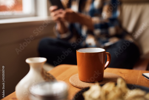 Close up of cup of coffee with woman in background.
