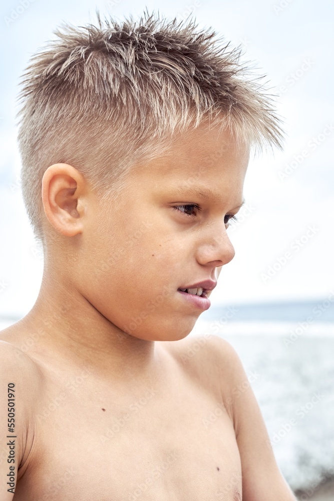 Boy with blue lips frozen from swimming in cold water at sea resort. Blond junior schoolboy gets cold after swimming against blue sky closeup Boy with blue lips frozen from swimming in cold water at sea resort. Blond junior schoolboy gets cold after swimming against blue sky closeup