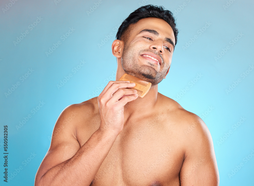 Fototapeta premium Beauty, model and beard face comb for handsome aesthetic with grooming, hygiene and wellness routine. Happy skincare man with facial hair tool in blue studio mockup for cosmetic advertising.