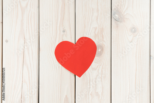 Small red handmade paper heart on white wood plank background. Donation, charity, open hearts of volunteers day. Healthcare and medicine aid, relief and humanitarian help. Flat lay, copy space