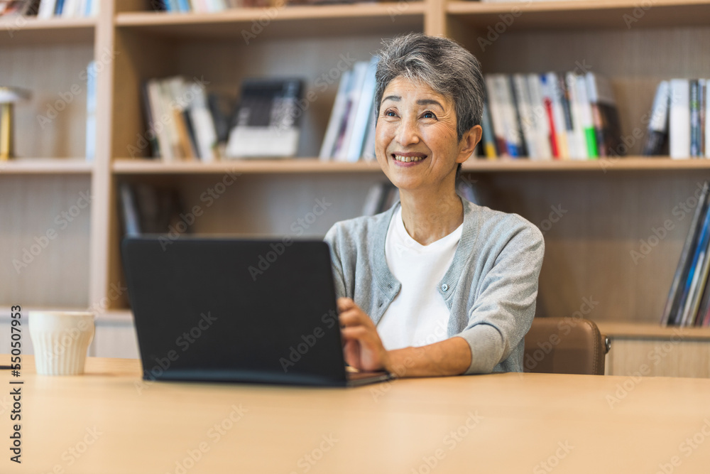 ノートパソコンと笑顔の日本人シニア女性