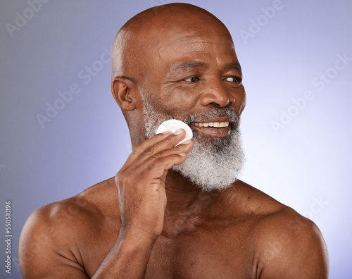 Face cotton, skincare and senior black man in studio on purple background. Beauty, wellness and elderly male model from Nigeria with facial pad or product for hygiene, cleaning and grooming beard.