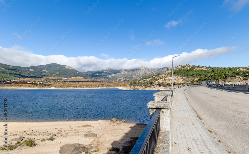 Navacerrada reservoir in autumn with the town in the background and the mountains of the Sierra de Guadarrama in Madrid