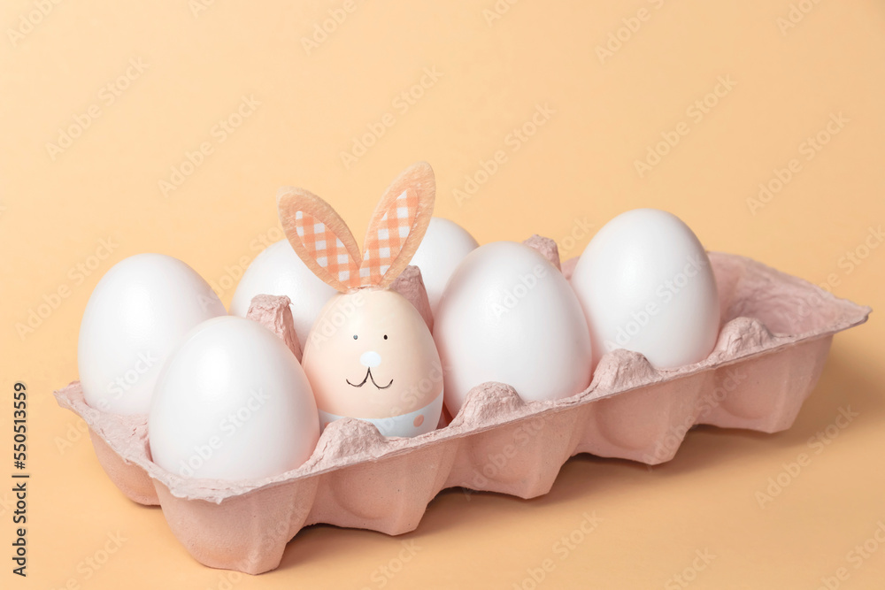 Fototapeta premium The Easter bunny is sitting in a box with white eggs. The concept of approaching the holiday.Festive composition.