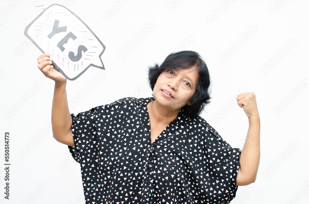 Portrait of happy ecstatic senior asian woman making yes winning gesture with raising her fist while holding yes bubble sticker isolated over white Portrait of happy ecstatic senior asian woman making yes winning gesture with raising her fist while holding yes bubble sticker isolated over white
