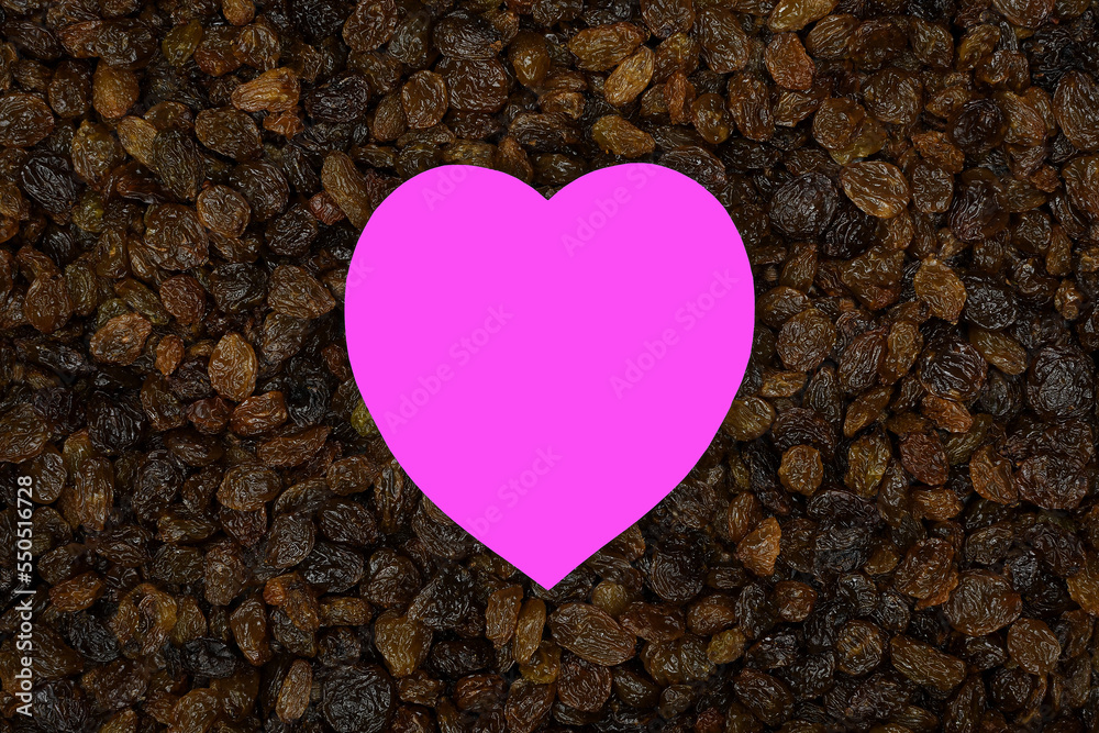 Obraz premium Vibrant pink love heart middle of fresh shiny brown Australian sun-ripened sultanas filling the frame 