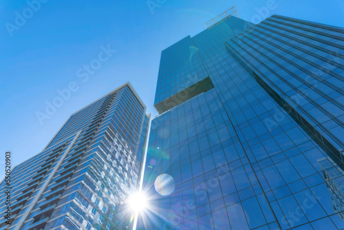 Modern glass residential buildings towering against sun and blue sky background