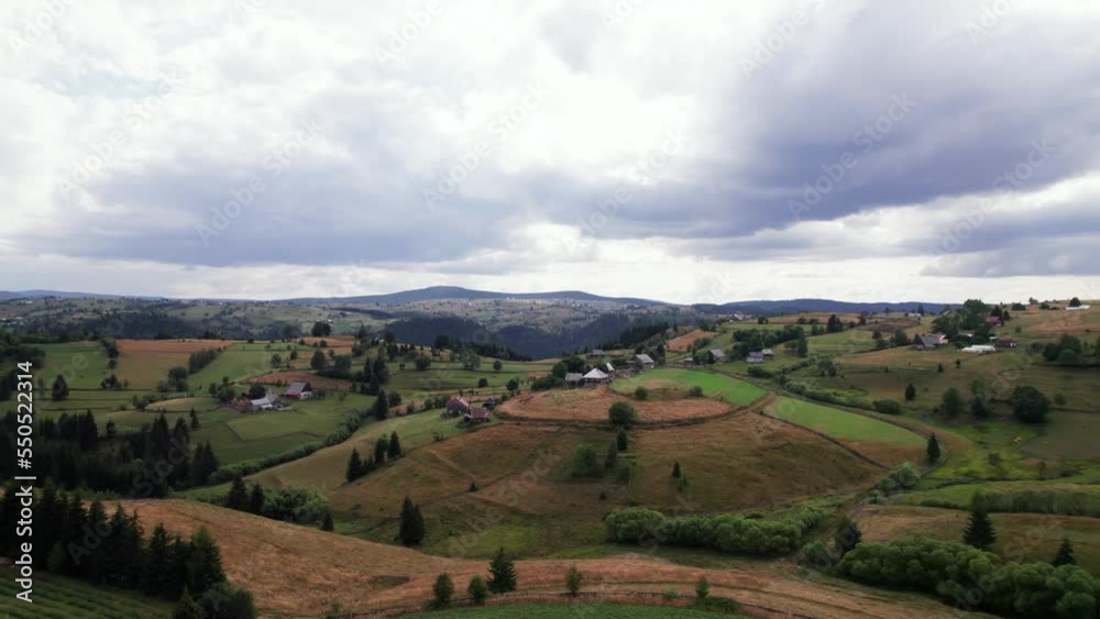 Aerial picturesque agricultural green hill land with houses in