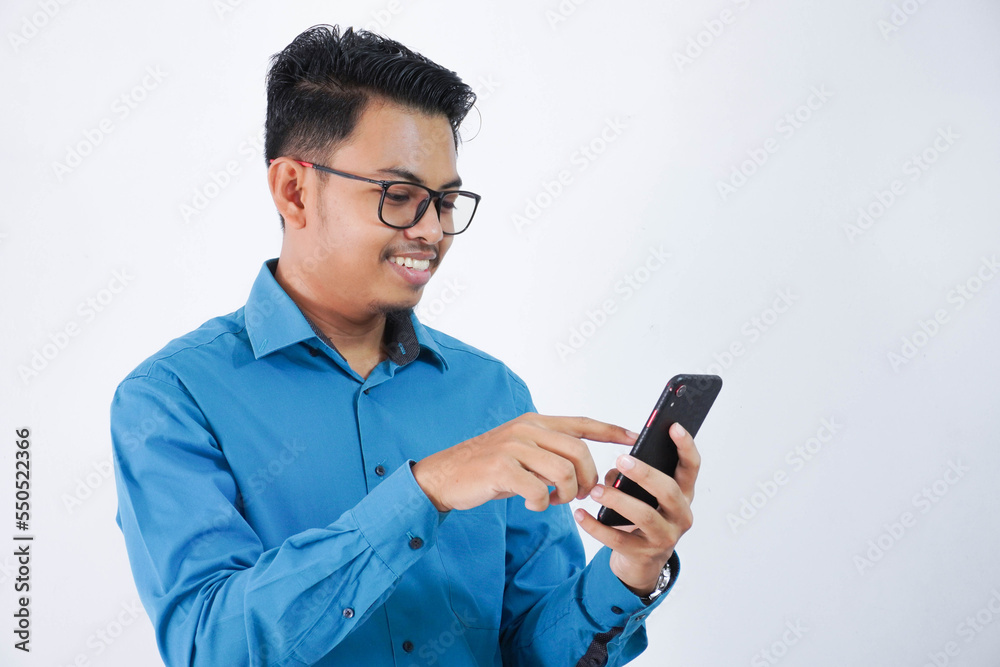 smiling asian employee man with glasses holding and touch the phone with finger wearing blue shirt isolated on white background smiling asian employee man with glasses holding and touch the phone with finger wearing blue shirt isolated on white background