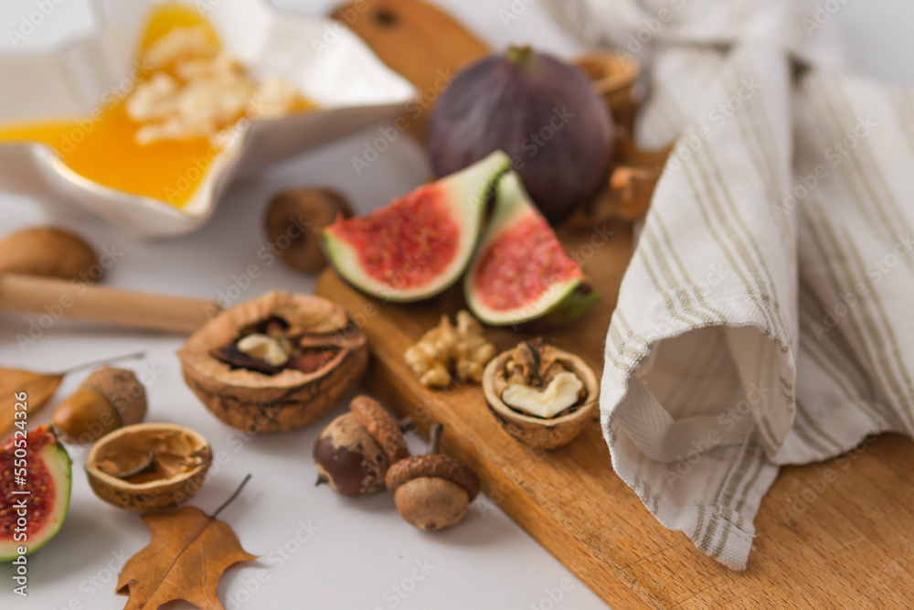 Autumn still-life with ripe figs cut in slices, walnuts and plate full of honey on wooden cutting board. Healthy snacks. Autumn still-life with ripe figs cut in slices, walnuts and plate full of honey on wooden cutting board. Healthy snacks.