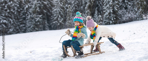 Fotografie Funny children in snow ride on sled