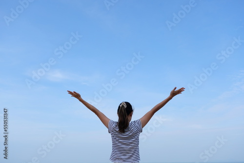 Woman on beach hold hands arms up, rear view guy wearing summer hat, standing back looking to sea blue sky horizon, vacation concept of freedom travel ocean