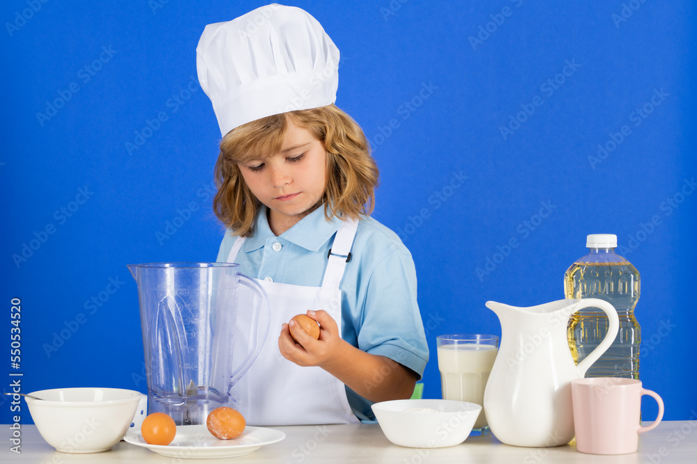 Child chef isolated on blue. Funny little kid chef cook wearing uniform cook cap and apron cooked food in the kitchen. Child chef isolated on blue. Funny little kid chef cook wearing uniform cook cap and apron cooked food in the kitchen.
