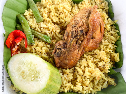 Nasi Kebuli or kebuli rice with fried chicken and vegetables.