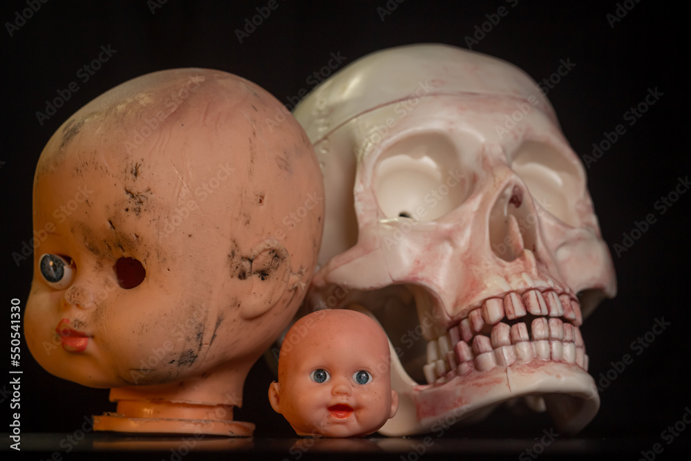 Damaged Dirty Doll head and skull on black background isolated Damaged Dirty Doll head and skull on black background isolated
