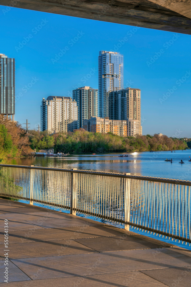 Austin, Texas- Views of boats on Colorado River and high-rise buildings from a pathway with railings