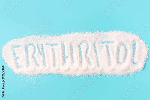Inscription erythritol on a sweetener close-up on a blue background top view.