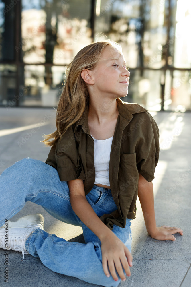 Portrait of teenage girl sitting on floor, urban street, sunlight Portrait of teenage girl sitting on floor, urban street, sunlight
