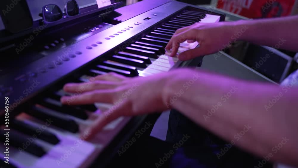 Close up shot over a male hands playing synthesizer at a function.