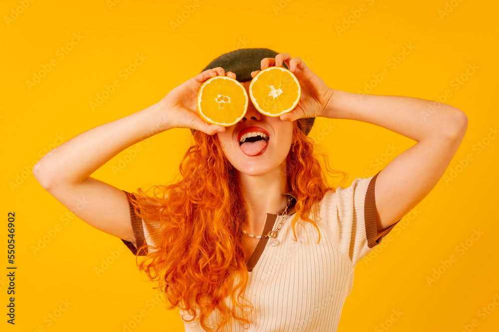 Teenager redhead girl holding an orange over isolated yellow background, covering her eyes Teenager redhead girl holding an orange over isolated yellow background, covering her eyes