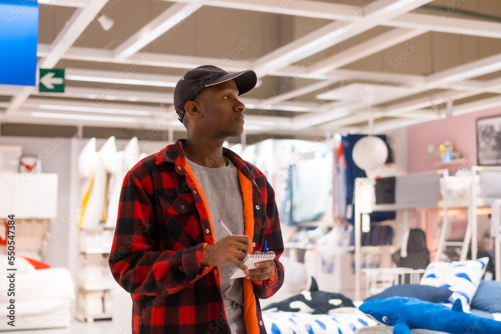 Obraz premium Black ethnic man shopping in a supermarket for almeadas and cushions. comparing prices