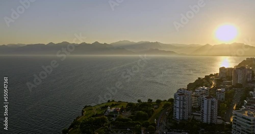 Antalya Turkey Aerial v20 flyover coastal park at fener neighborhood, sun setting behind the mountain with beautiful golden sunset reflection on mediterranean sea - Shot with Mavic 3 Cine - July 2022 photo