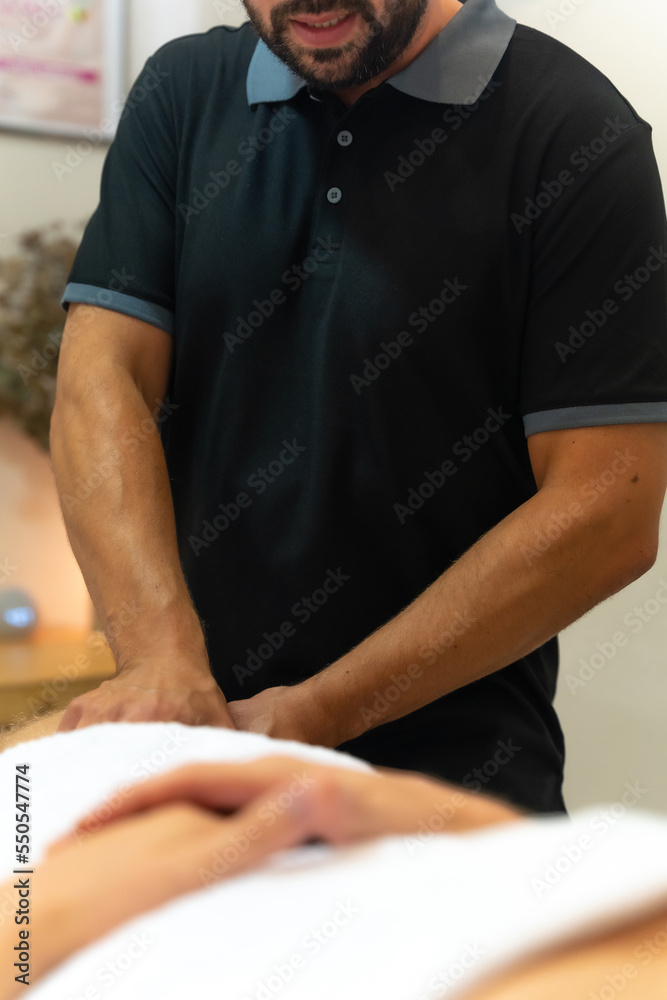 Detail of a physiotherapist doing a physiotherapy massage to the blond client in the thigh