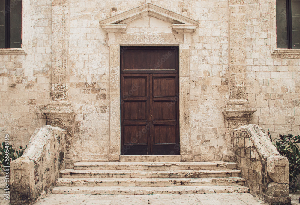 Fototapeta premium Chiesa SS. Pietro y Paolo (iglesia de San Pedro y San Pablo en italiano), Monopoli, Italia. Puerta de entrada a la iglesia con la piedra envejecida por las condiciones meterológicas.