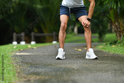 Cropped shot of tired sportsman taking a break, resting after running in the park. Healthy lifestyle, workout and wellness concept © Prathankarnpap