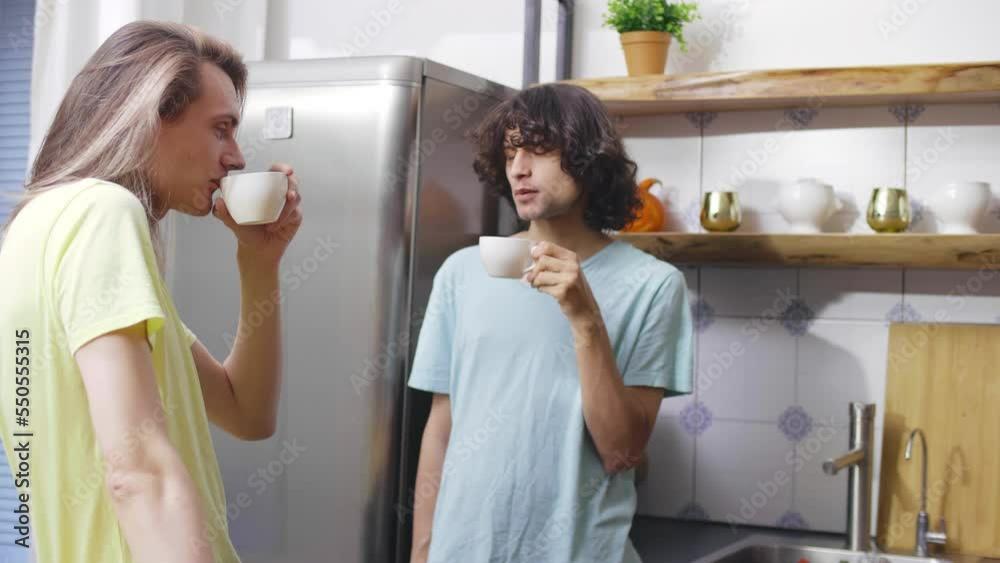 Roommates drink coffee and talk standing in kitchen in morning. Realtime Roommates drink coffee and talk standing in kitchen in morning. Realtime