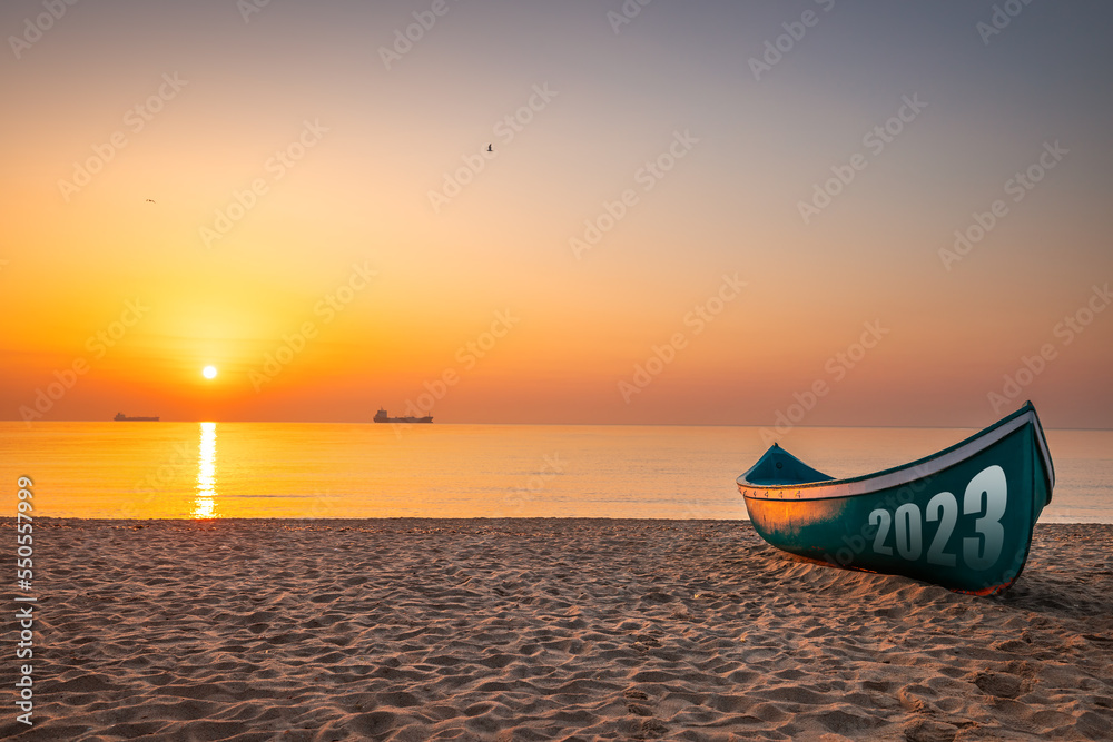 Fototapeta premium Happy new year 2023 relaxation morning on the beach concept. Fishing Boat and beautiful new sunrise or sunset on the seashore.