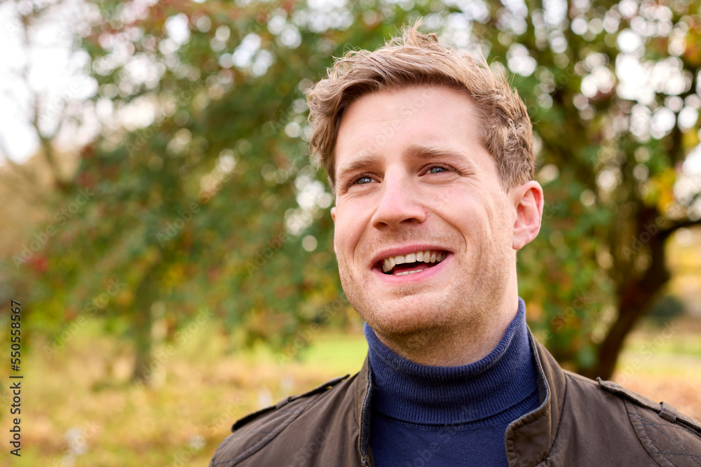Smiling Young Man Wearing Coat Standing Outside In Autumn Or Winter Countryside Smiling Young Man Wearing Coat Standing Outside In Autumn Or Winter Countryside