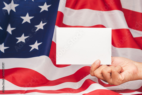 Hand holding a blank white paper against the American flag background