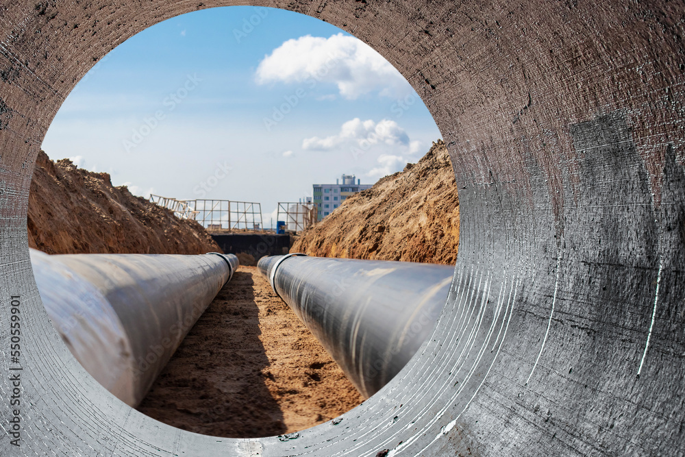 Modern water supply and sewerage system. Underground pipeline works. Water supply and wastewater disposal of a residential city. Close-up of underground utilities. View from the big pipe. - obrazy, fototapety, plakaty 