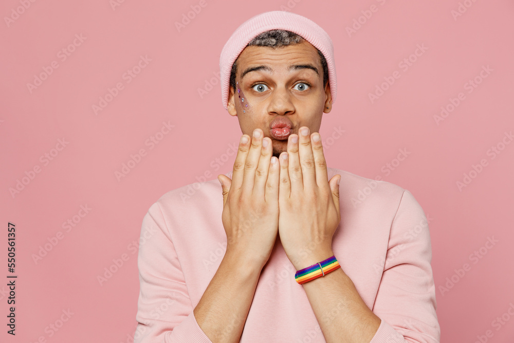Young shocked surprised amazed astonished gay man wear sweatshirt hat hold hands near mouth cover isolated on plain pastel light pink color background studio portrait. Lifestyle lgbtq pride concept. Young shocked surprised amazed astonished gay man wear sweatshirt hat hold hands near mouth cover isolated on plain pastel light pink color background studio portrait. Lifestyle lgbtq pride concept.