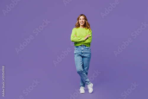 Full body smiling young woman 30s she wearing casual green knitted sweater hold hands crossed folded look camera isolated on plain pastel purple background studio portrait. People lifestyle concept.