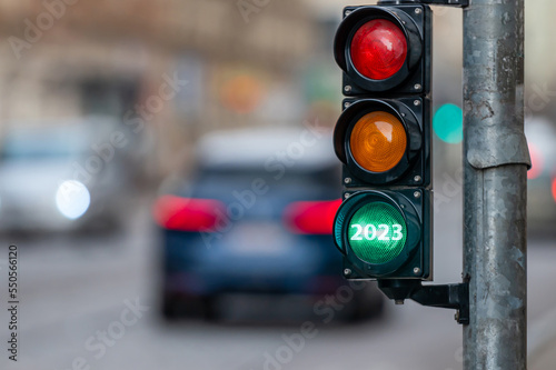 view of city traffic with traffic lights, in the foreground a semaphore with a green light, closeup