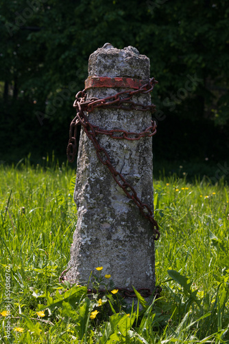 A lopsided gray cement post wrapped in grim