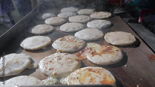 Pupusas a traditional salvadoran food being cooked in hot griddle close up. photo