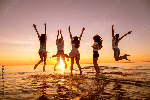 Group of happy young girls are having fun and jumping at sunset beach