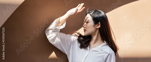 Portrait of young beautiful asian woman traveler hands protect face from sun light in fresh summer time. Happy cheerful asian girl in summer. Beauty sunscreen skin care make up model concept