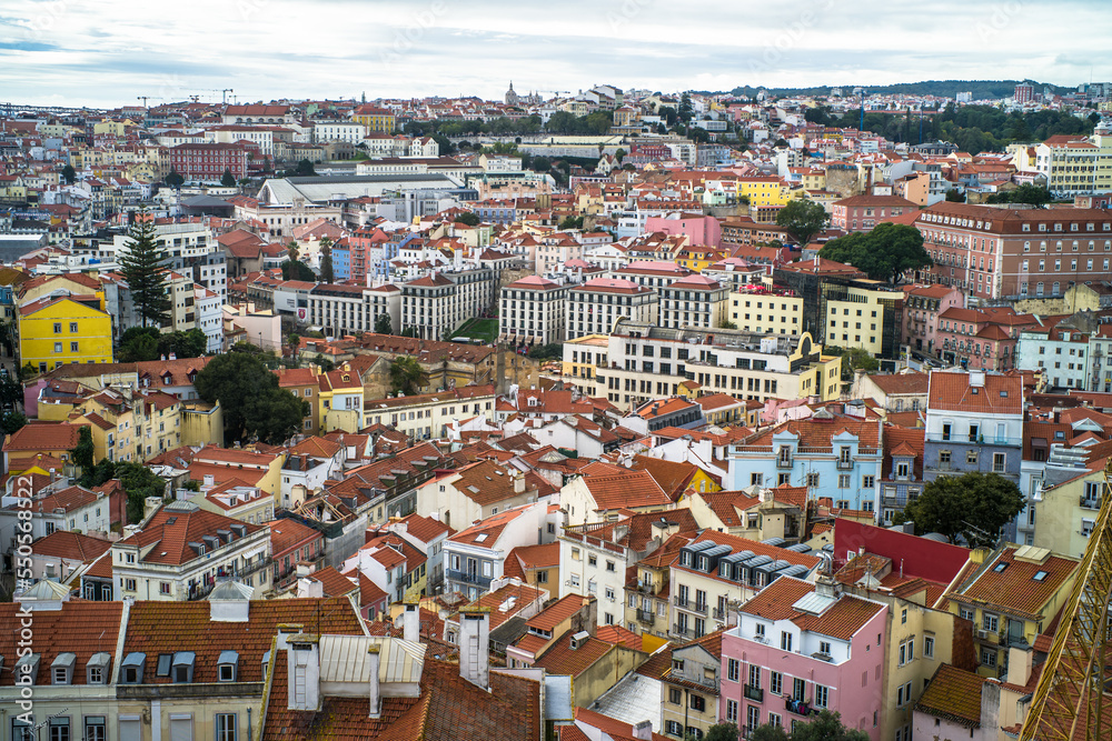 historic buildings of the old town of lisbon. Old colorful buildings, narrow streets, historic churches. Tiled roofs. View from the top of the tenement houses and monuments. Cloudy day
