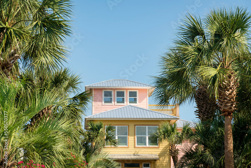 Three-storey house with pastel pink and yellow painted wood siding in Destin, Florida © Jason