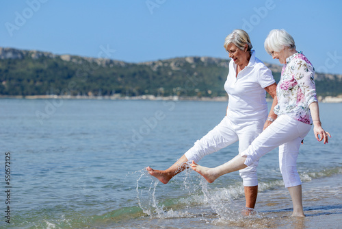coppia di signore anziane giocano divertite sulla riva del mare