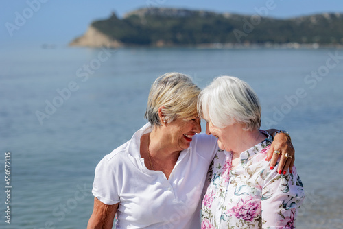 coppia di signore anziane abbraccia affettuosamente sulla riva del mare