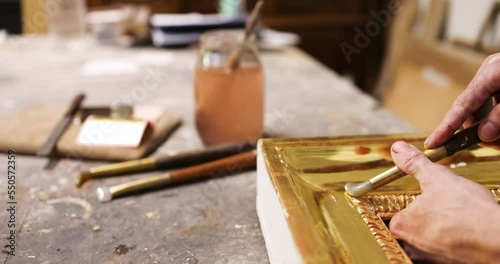 Hand of frame mker polishing gilded frame with agate