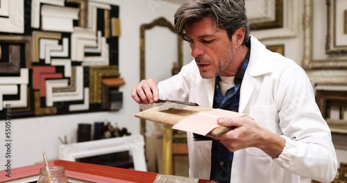 Frame maker cutting silver leaf for picture frame