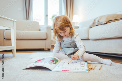 Happy little girl drawing at home. Happy child plays. Little child girl draws with colored pencils. Little girl drawing with colorful pencils.